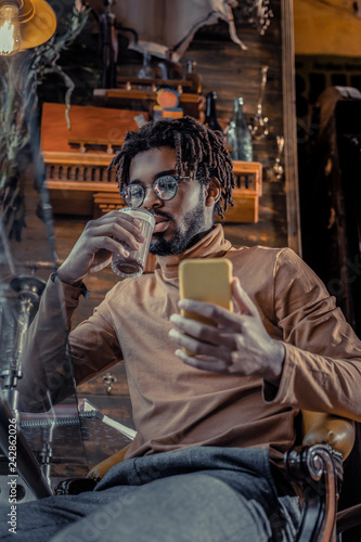 Handsome bearded freelancer drinking cacao in cafe