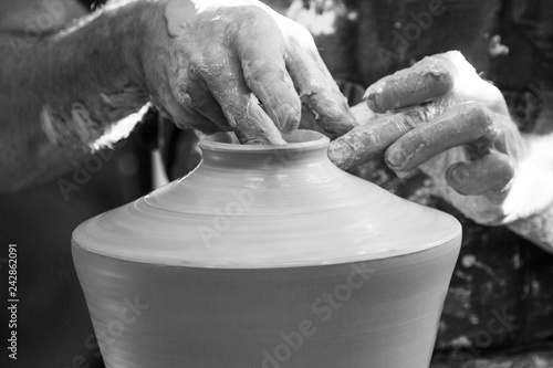 Detail of artist potter in the workshop sculpting ceramic vase, black and white 