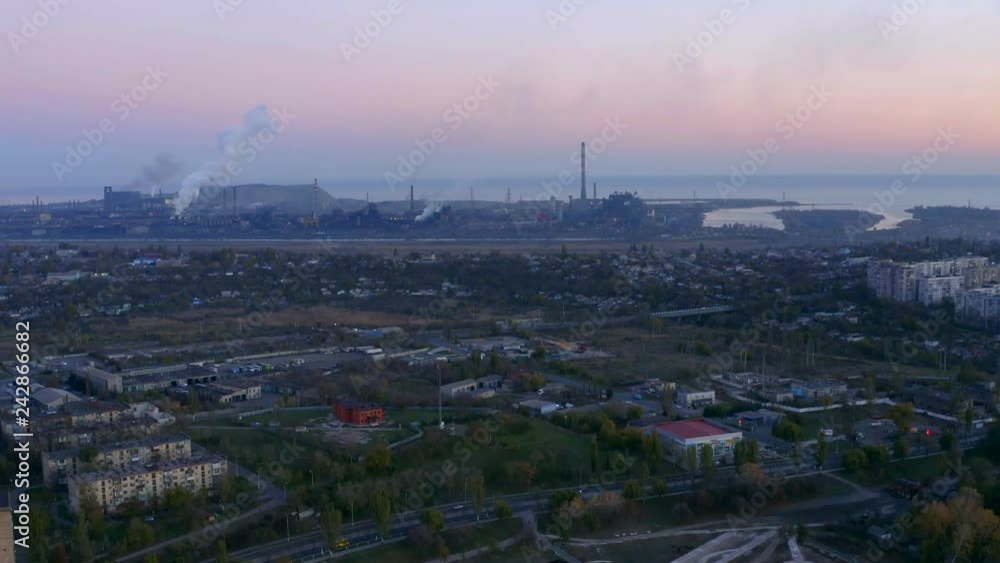 Evening time. Bird's eye view of metallurgical plant. The plant is located in the city by the sea. Evening time. Bird's eye view of metallurgical plant. The plant is located in the city by the sea.