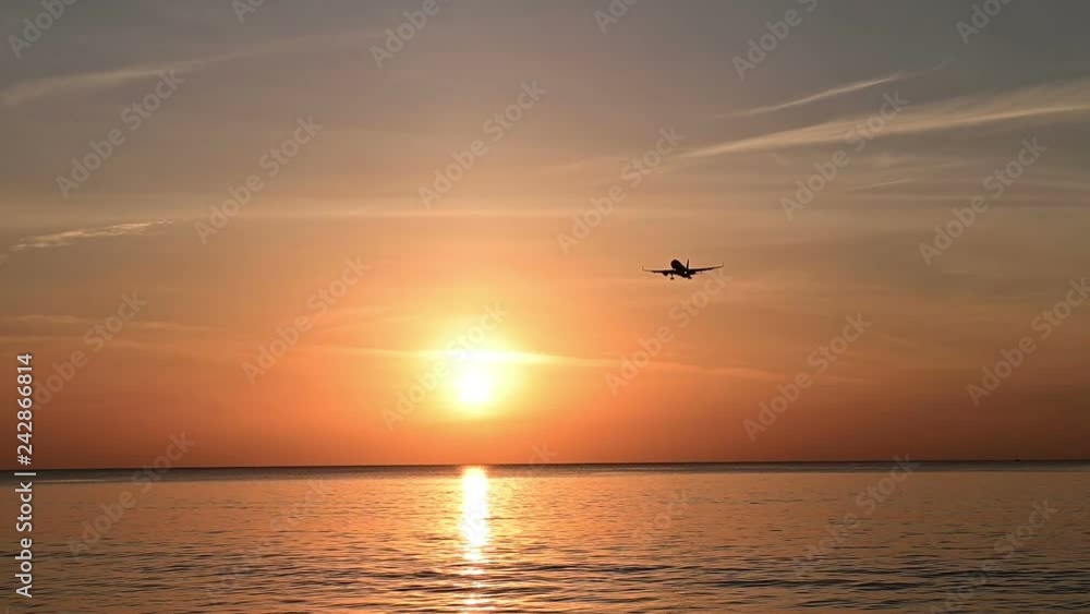 Silhouette of airplane flying slow motion for landing at the airport with ocean view Silhouette of airplane flying slow motion for landing at the airport with ocean view