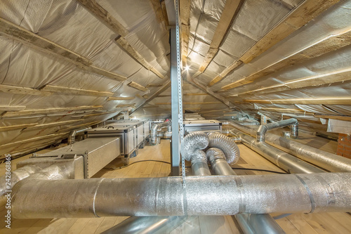 Whole house air ventilation and cleaning system. Ventilation pipes in silver insulation material on the attic