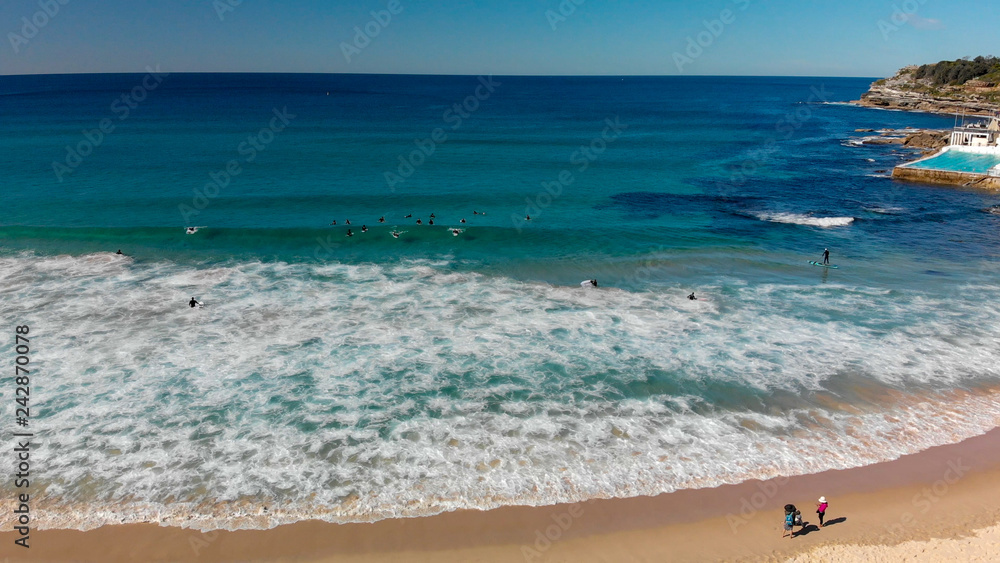 Aerial view of Bondi Beach coastline with surfers and waves, Sydney, Australia.