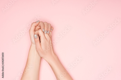 cropped view of folded female hands isolated on pink