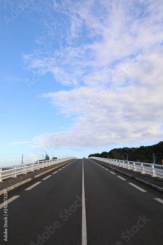 Straight and smooth asphalt road with one continuous marking. Blue sky background