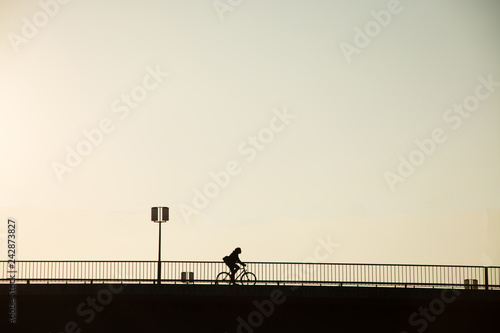 silhouette bicycle of bicycle rider on the bridge against sunset, minimalistic urban landscape 