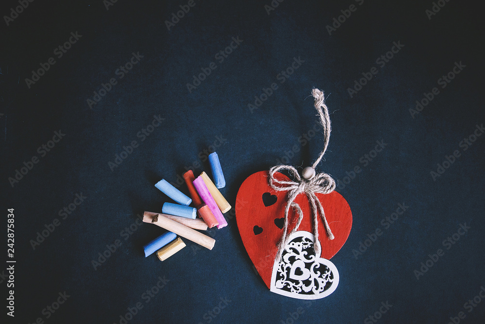 handmade red heart close-up and pieces of pastel chalks on dark background, symbol of love, happy Valentine's day