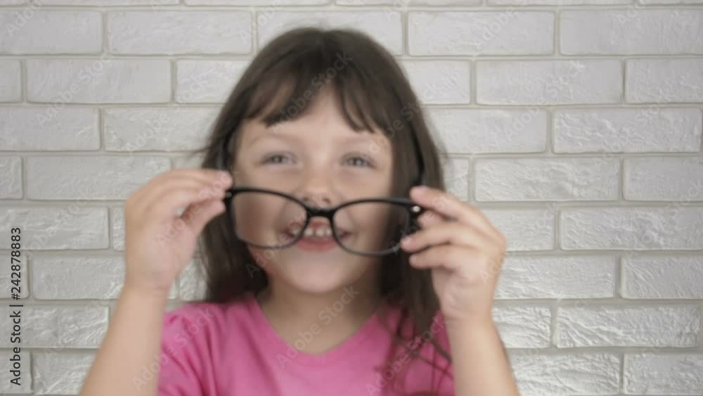 Cheerful child with glasses. Adorable little girl puts on glasses. Cheerful child with glasses. Adorable little girl puts on glasses.