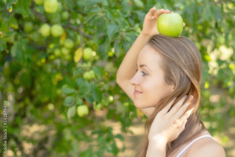 Summertime in garden. Young woman is holding a juicy green apple in her hand. Summertime in garden. Young woman is holding a juicy green apple in her hand.