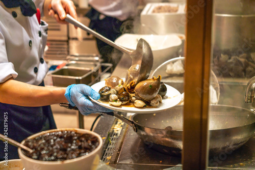 Chef cooking seafood, clams, cockle in the buffet restaurant