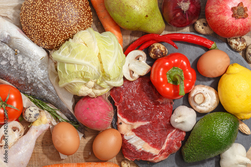 Healthy food clean eating selection: fruit, vegetable, seeds, fish, meat, leaf vegetable on wooden background. Top view.