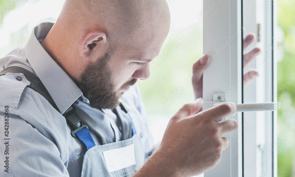 Fototapeta premium Young repairman fixing window frame in room at daytime