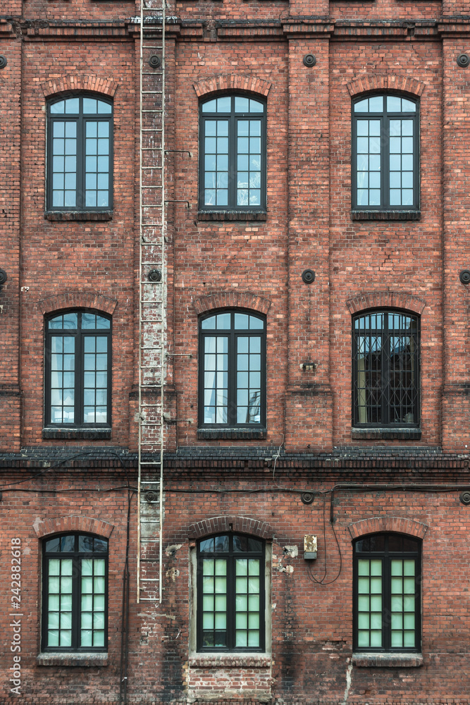 Fototapeta premium Żyrardów, Poland. Window with iron frame and red bricks wall of old factory.