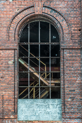 Żyrardów, Poland. Window with iron frame and red bricks wall of old factory.