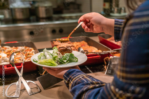 Woman hand choosing huge Beef steak in the buffet