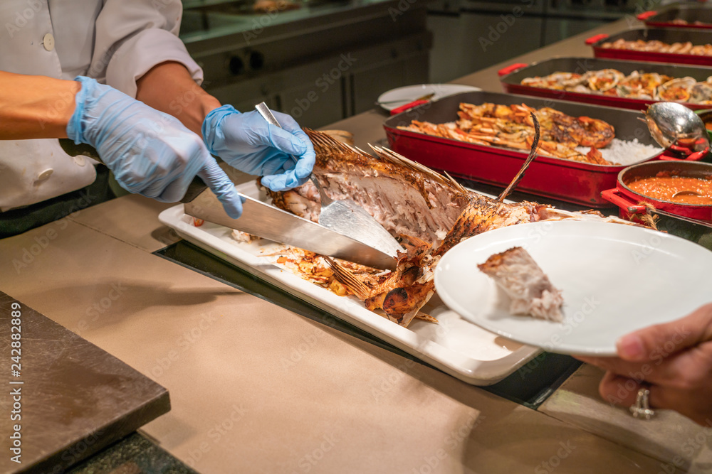 Chef slicing and cutting Grilled fish in the buffet restaurant