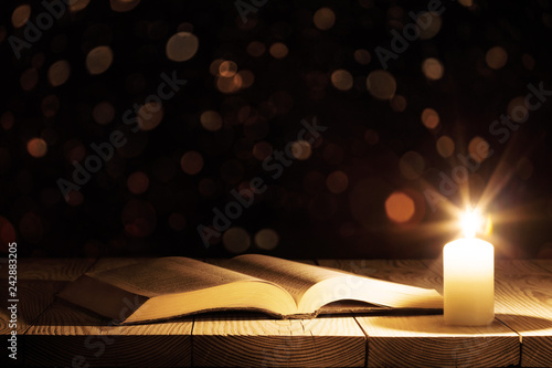 a bible on the table in the light of a candle