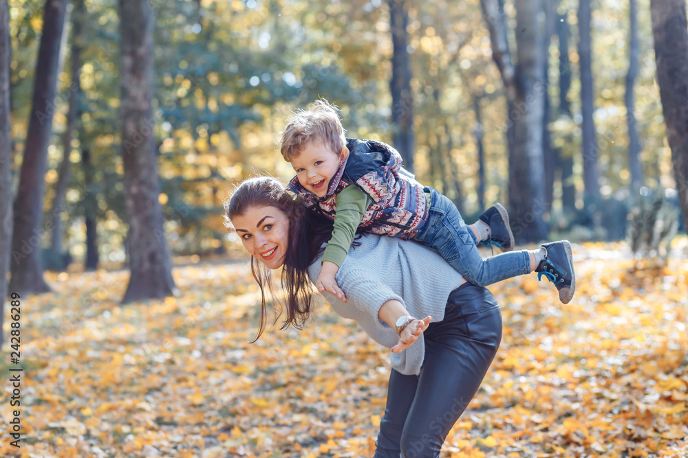 Mom and son having fun in the park in autumn