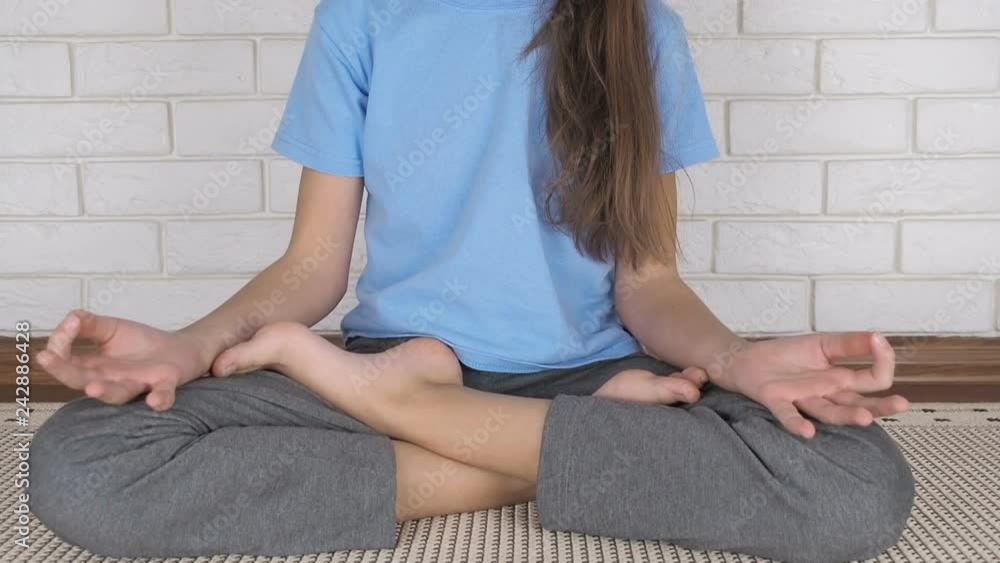 A child practices yoga. Teenage girl meditates in the lotus position. A child practices yoga. Teenage girl meditates in the lotus position.