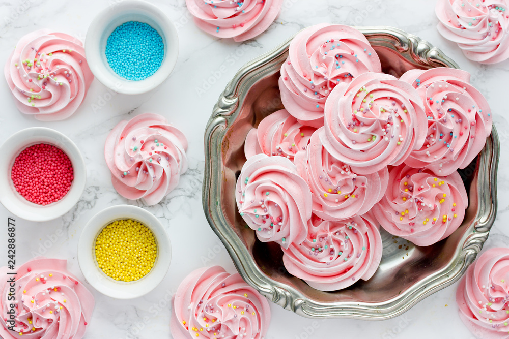 Swirled pink meringue with coloured sugar sprinkles, beautiful meringue kisses for sweet treats Swirled pink meringue with coloured sugar sprinkles, beautiful meringue kisses for sweet treats