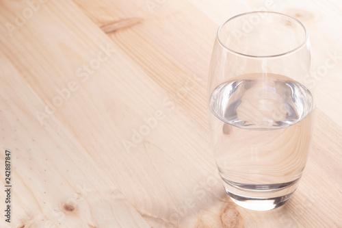 Image of a glass half full of water standing on a wooden table
