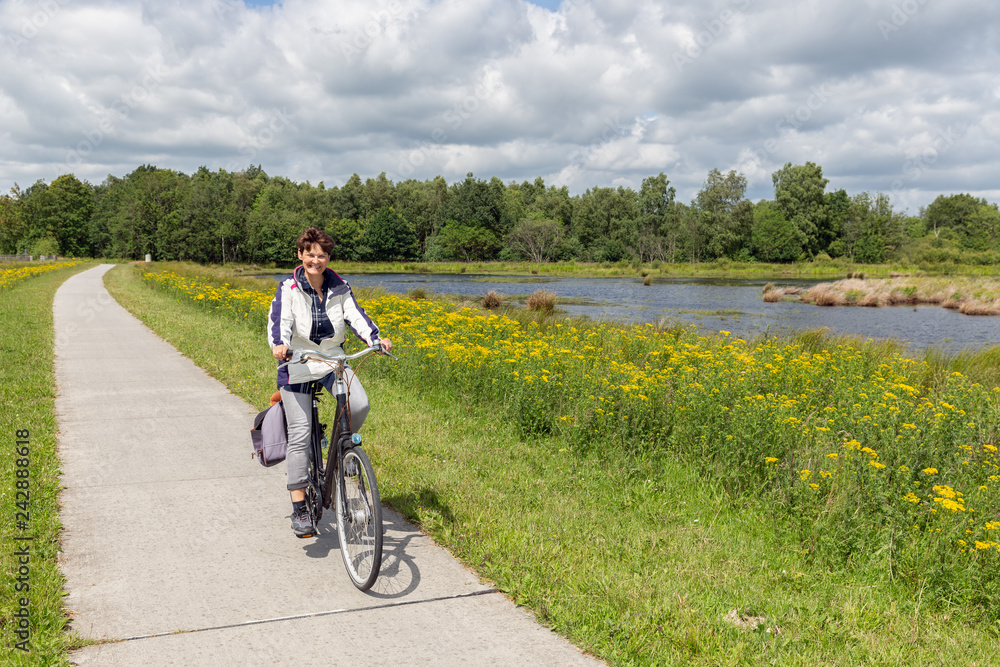 Biking woman in Dutch national park with forest and wetlands
