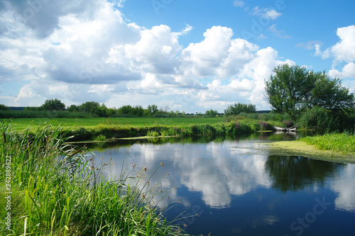 river, land with trees and cloudy sky