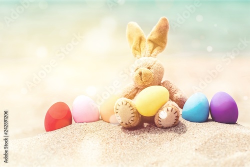 Easter bunny and color eggs on the sandy beach by the ocean