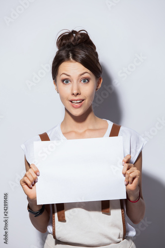 Smiling young pretty woman showing blank signboard, over white background isolated.