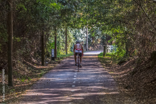 Fototapeta Naklejka Na Ścianę i Meble -  Man cycling on pedestrian cycle path, path with vegetation around