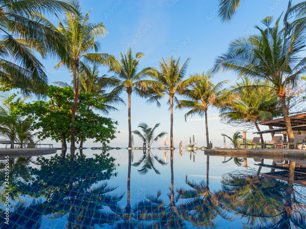 The palm trees from the seashore are reflected in the pool water The palm trees from the seashore are reflected in the pool water