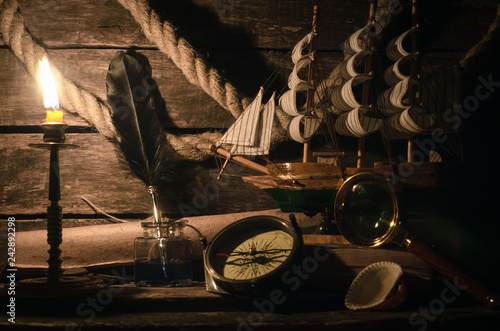 Sea adventure concept background. Pirate captain table. Marine ship, quill pen in a inkpot, compass and magnifying glass on the table.