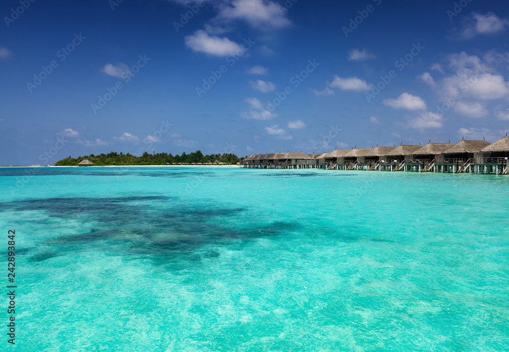 Obraz premium Widok laguny na Malediwach z turkusem, tropikalną wodą i głębokim błękitnym niebem