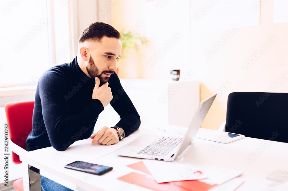 Thoughtful caucasian young man working on laptop computer Thoughtful caucasian young man working on laptop computer
