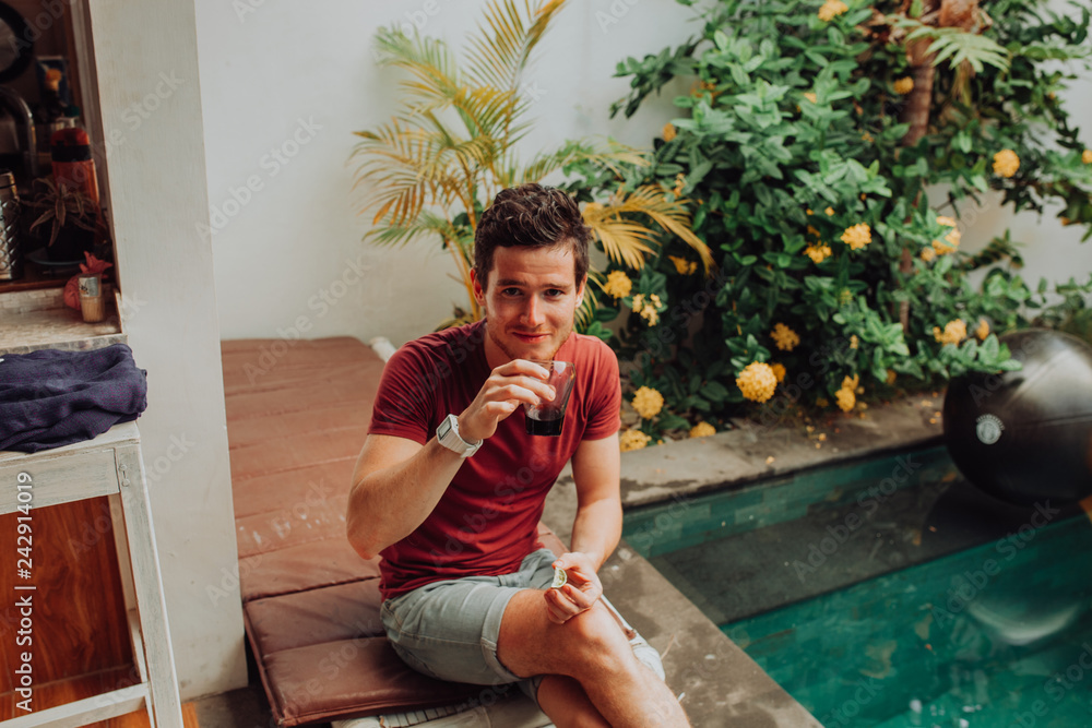 Fototapeta premium men eat crisps by swimming pool, man in swim pool with cocktails