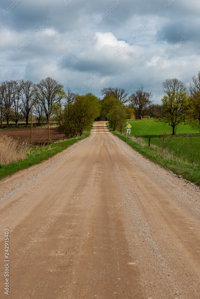 country gravel road with old and broken asphalt