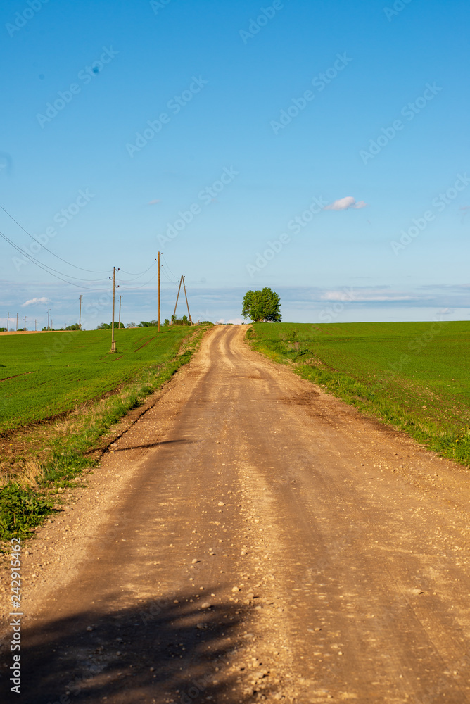 country gravel road with old and broken asphalt