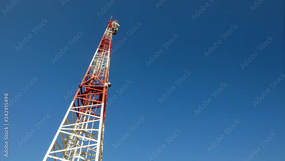 Looking up to small red and white telecommunications tower, communication dishes on top. Abstract technology background, space for text on right. Looking up to small red and white telecommunications tower, communication dishes on top. Abstract technology background, space for text on right.