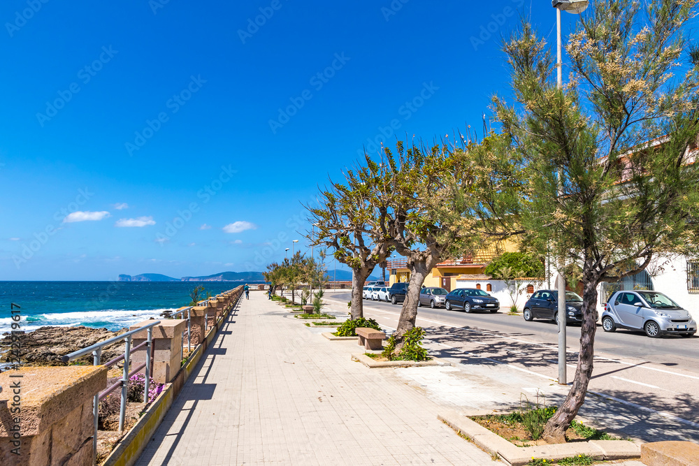 Sunny view of sea promenade and the old walls of Alghero city, Sardinia, Italy. Mediterranean seacoast