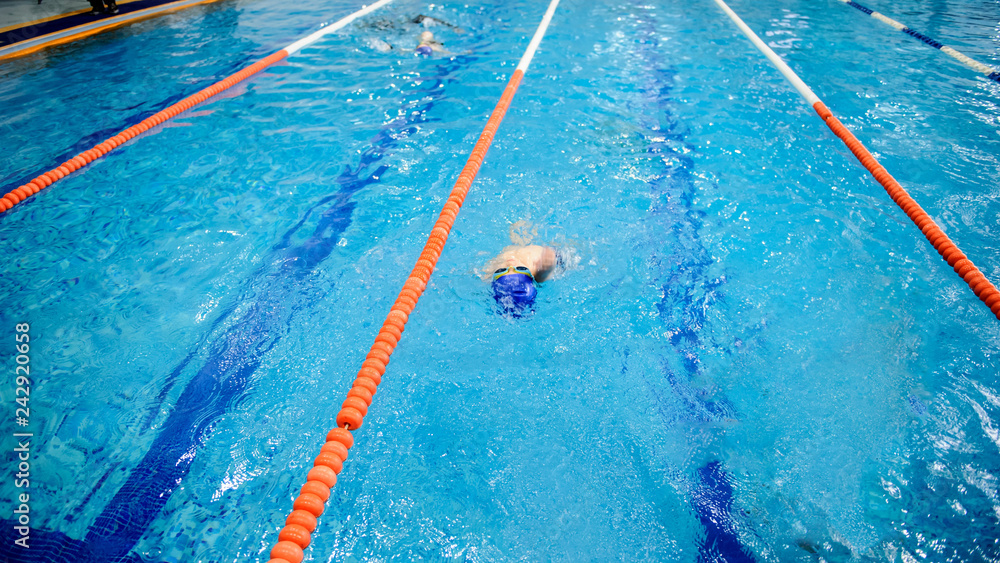 a 6-year boy swims backstroke in a swimming pool for competition