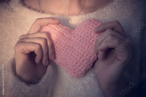 The girl holds in her tender hands a knitted homemade heart