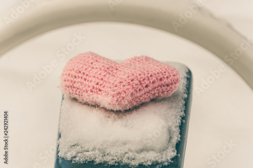 Homemade knitted pink heart on snow-covered swings