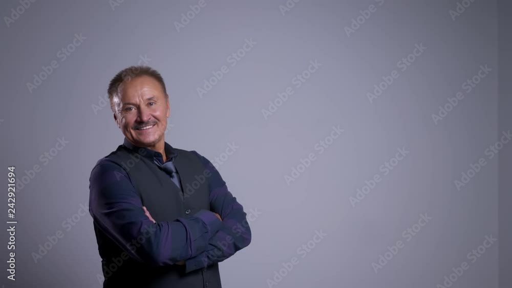 Portrait of glad senior man smiling having his arms crossed over chest and looking at camera Portrait of glad senior man smiling having his arms crossed over chest and looking at camera