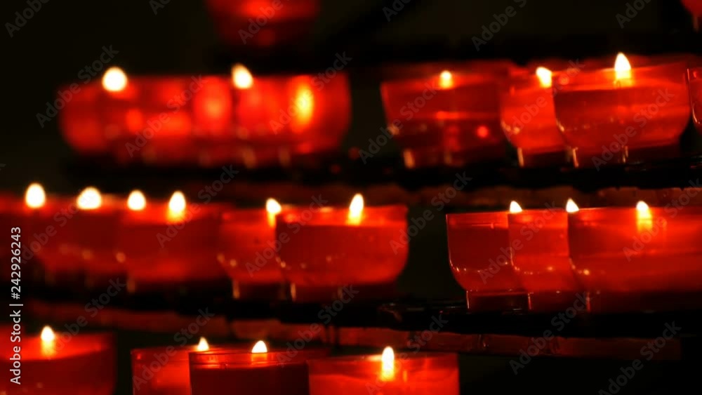 Row of christian prayer red round votive candles burn in the dark. Prayer lighting Sacrificial Candles close up. Burning memorial candles in Catholic church. Celebrating christmas in Cathedral Row of christian prayer red round votive candles burn in the dark. Prayer lighting Sacrificial Candles close up. Burning memorial candles in Catholic church. Celebrating christmas in Cathedral