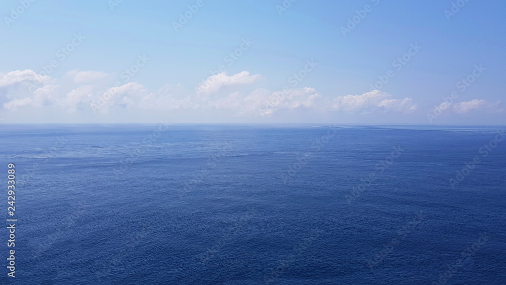 Fototapeta premium Against the horizon is a calm sea, above the horizon are bright clouds. 