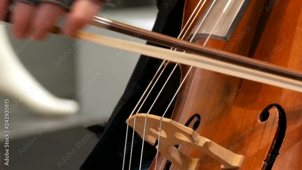 Street musician playing the cello close up view. Cellist in gloves gently bows strings Street musician playing the cello close up view. Cellist in gloves gently bows strings