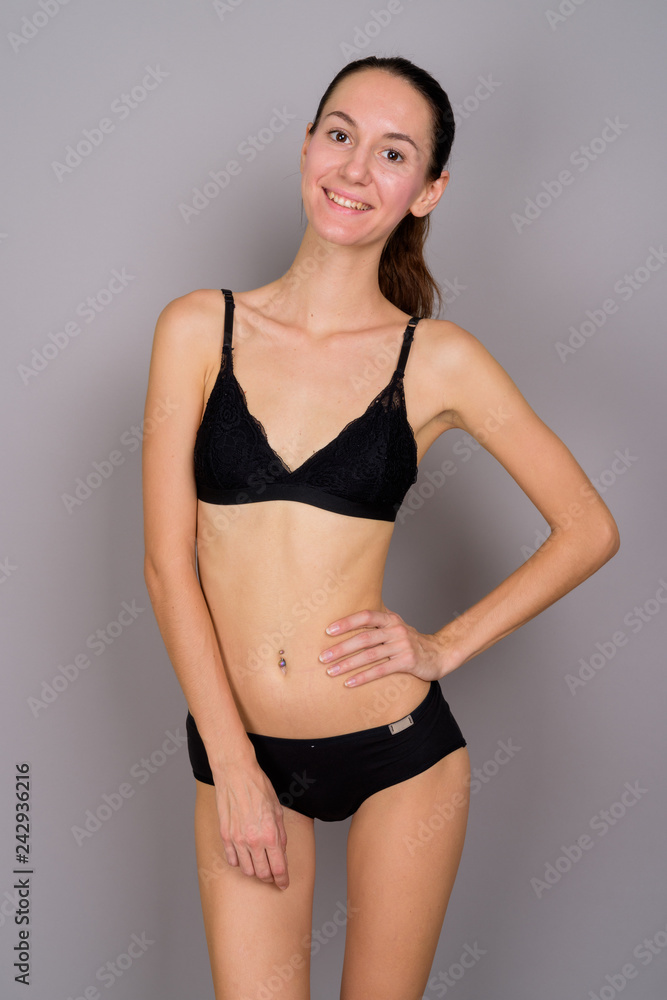 Young beautiful woman in lingerie smiling against gray background Young beautiful woman in lingerie smiling against gray background