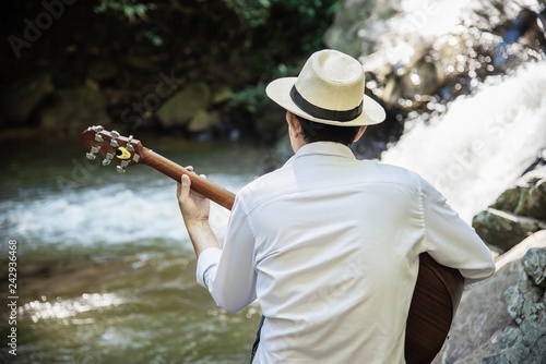 Man play ukulele new to the waterfall - people and music instrument life style in nature concept © pairhandmade
