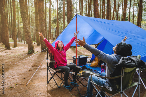 young asian couple of happy enjoying Camping in the pine forest Sit and eat food at the Camping page in the midst of nature.