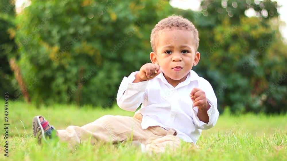 Cute child playing and have fun on the lawn. Funny little afro-american kid is getting to know to the natural world. Cute little kid playing outside. Cute child playing and have fun on the lawn. Funny little afro-american kid is getting to know to the natural world. Cute little kid playing outside.