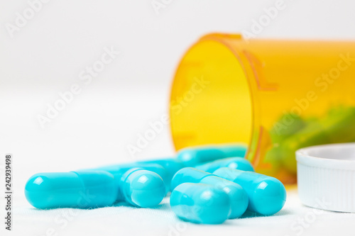 Blue medicine pills spilling out of bottle